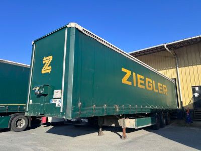 une semi-remorque verte garée devant un immeuble