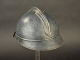 a silver helmet on a metal stand on a gray background