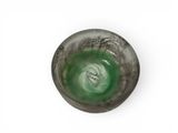 a green glass bowl with writing on it on a white surface