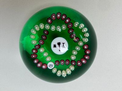 une boule en verre verte ornée de fleurs rouges et blanches