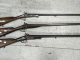 cinq armes à feu sont alignées sur une table dans une pièce