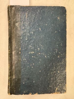 un vieux livre posé sur une table, à côté d'une feuille blanche