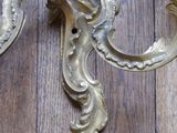 a gold wall sconce on a wood floor next to a wall