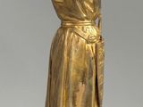 gold figurine of a man in a robe and hat holding a book