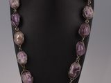 un collier composé de perles violettes et blanches, présenté sur un mannequin noir