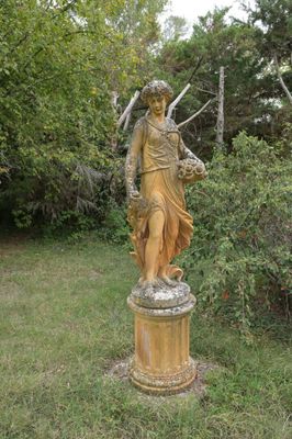 une statue représentant une femme debout dans l'herbe