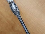 une cuillère en argent avec un manche en argent posée sur une table en bois