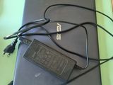 un ordinateur portable posé sur une table, avec son chargeur branché