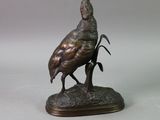 a bronze statue of a bird sitting on a tree branch