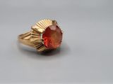 a close up of a gold ring with a red stone