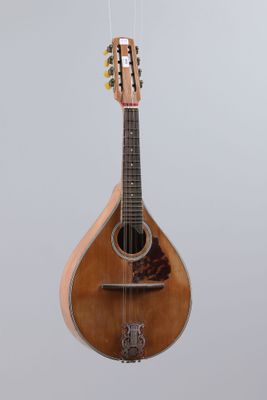 an old guitar hanging from a string on a gray background