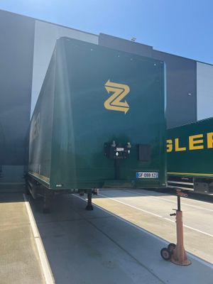 un grand camion vert garé devant un immeuble