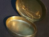 a small gold box with a picture of a woman on it