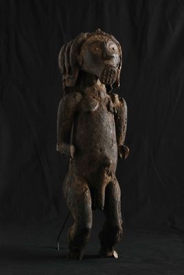 une statue en bois représentant un chien à la tête et aux pattes imposantes