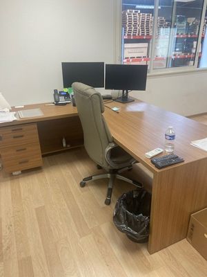 a desk with two computer monitors and a bag on it