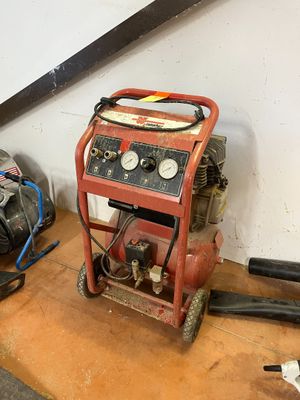un petit compresseur d'air posé par terre à côté d'autres outils