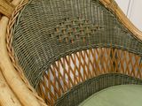 une chaise en osier avec un coussin vert dans une pièce