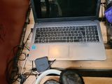 un ordinateur portable posé sur une table en bois, avec un casque de musique autour de lui
