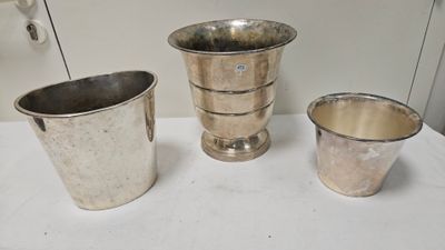 trois vases en argent posés les uns à côté des autres sur une table