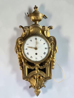a gold clock hanging on the wall with a crown on top