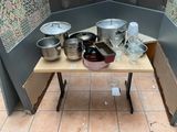 de nombreuses casseroles et poêles posées sur une table dans un coin de la pièce