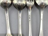 four spoons and a fork are lined up on a table