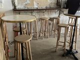 tables and stools in a small room with a laptop on a stand
