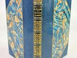 un vieux livre à la couverture bleue, rehaussée de dorures sur fond blanc