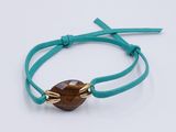 a bracelet with a brown glass bead on a turquoise cord