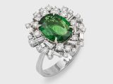 gros plan d'une bague avec une pierre verte entourée de diamants blancs