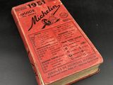 an old red book sitting on top of a table next to a black table