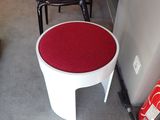 un tabouret blanc avec une assise rouge au milieu d'une pièce