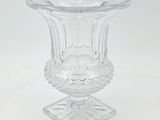a clear glass vase on a stand on a white surface