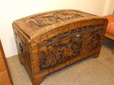 an old wooden chest sitting on top of a carpeted floor next to a chair