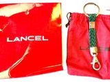 a red bag with a green rope and a red bag with a lancel on it