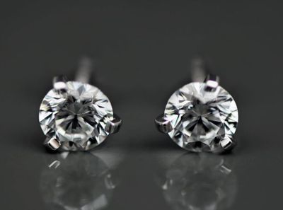 a pair of diamond earrings on a reflective surface