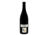 the bottle of red wine is sitting on a white surface