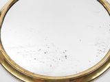 a round mirror with a gold frame on a white surface