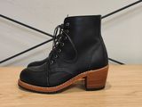 une paire de bottes en cuir noir posée sur une étagère en bois