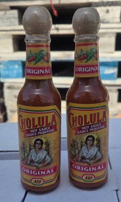 two bottles of hot sauce sitting on top of a table