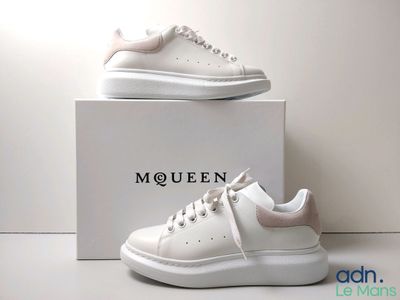the white sneakers are on a white box with a logo on it