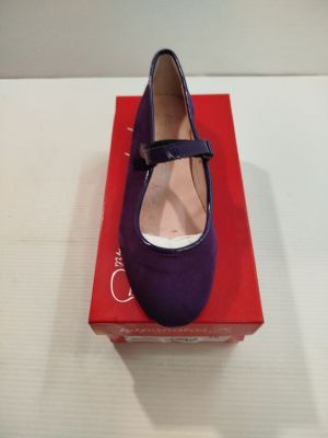 des chaussures violettes posées sur une boîte rouge, elle-même posée sur une surface blanche