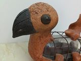 sculpture of a bird with a bottle in its beak sitting on a table