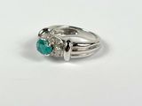 a close up of a diamond and emerald ring on a white surface