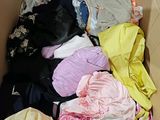 a cardboard box filled with lots of different colored clothes