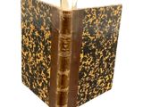 un vieux livre à la couverture brune posé sur une surface blanche