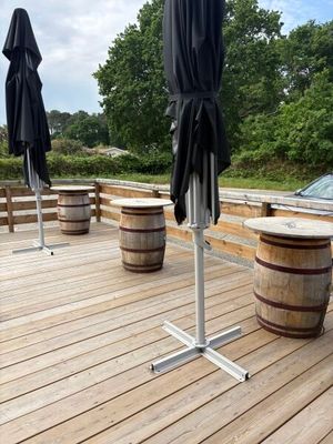 deux parapluies sur une terrasse en bois, avec des tonneaux en bois