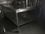 une grande table en acier inoxydable au milieu d'une cuisine