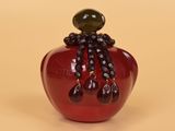 a red apple with a black beaded decoration on it