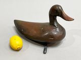 a wooden duck sitting next to a lemon on a table